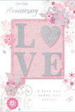 This image shows an anniversary card designed with the same quiet elegance you might find in a discreet Knightsbridge boutique, where personal gestures matter as much as luxury. At the centre of the card, the word LOVE is displayed in large, raised letters whose surfaces are delicately dusted with fine glitter. The colours shimmer between blush pink, pearlescent white, and refined silver, creating a soft, romantic glow reminiscent of early evening light over nearby Hyde Park. The tactile embossing makes the letters feel almost sculpted, inviting gentle touch. Flowing outwards from this central word, a halo of illustrated blossoms, curling vines, and slender leaves sweeps across the card. These flowers are not loudly realistic but stylised, drawn with fine, calligraphic lines and shaded in soft greys and pale pinks over a warm, powder-pink background, much like a florist's initial sketch for an anniversary bouquet destined for a quiet mews off Knightsbridge Road. The floral sprays gather at the edges and corners, then taper into delicate curls that frame but never overshadow the wording. In elegant script, anniversary sentiments are woven between the motifs, expressing deep affection, gratitude for shared years, and hope for many more seasons together. Gentle lighting in the photograph enhances the card's shimmer and soft pastel tones, giving the whole composition a dreamy, almost ethereal character. It feels like a paper bouquet-subtle, romantic, and enduring-perfect to accompany flowers delivered to a loved one in Knightsbridge, where understated gestures speak volumes.
